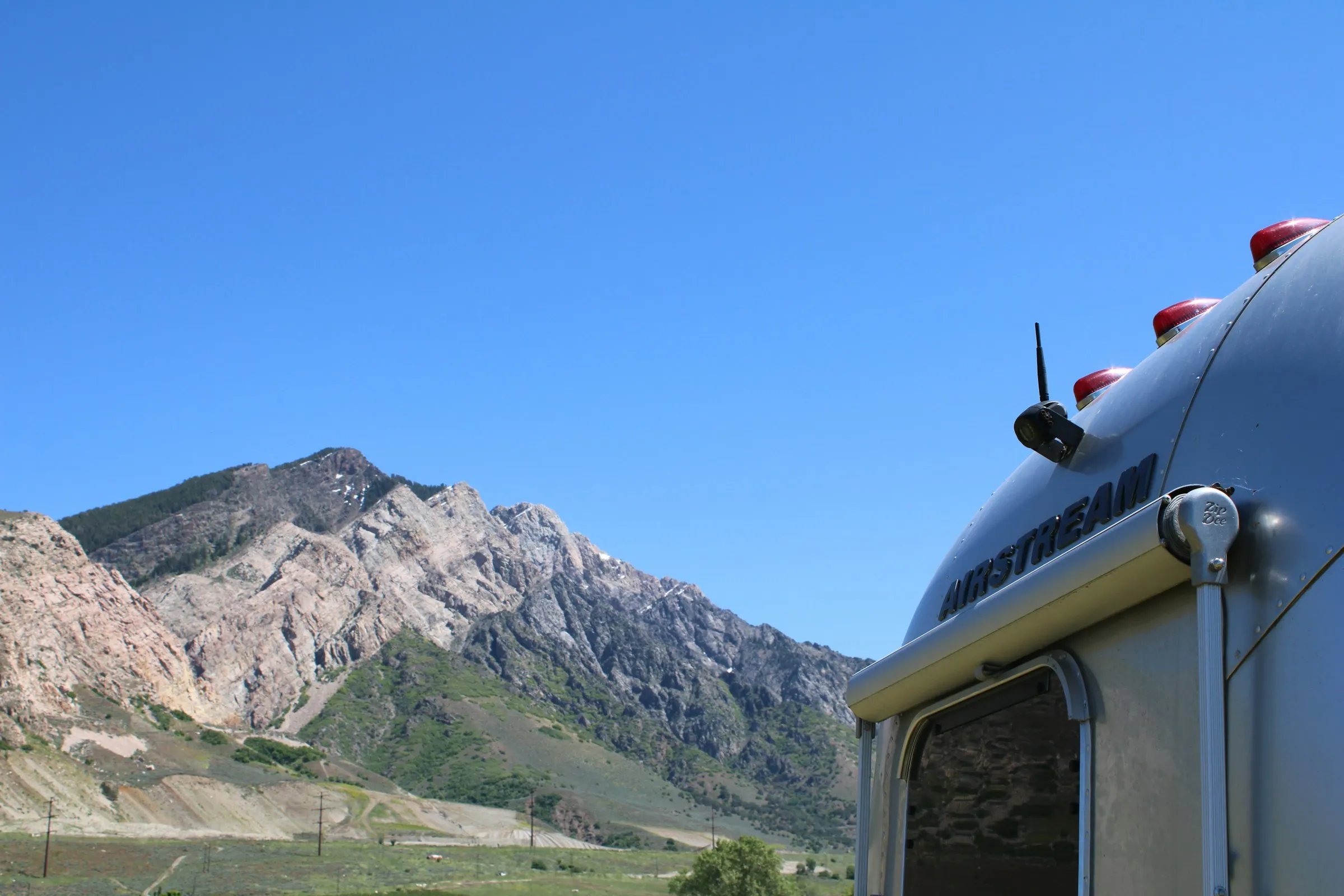 A polished Airstream travel trailer parked below a mountain ridge